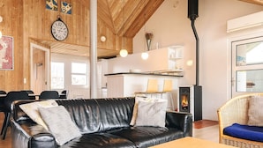 A cozy living area with a leather sofa, wooden ceiling, and a fireplace.