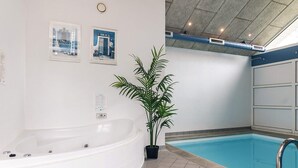 A spa area with a bathtub, a pool, and a potted plant.