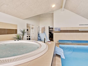 A swimming pool with a hot tub, a slide, and a small table with a bottle and glasses. - 5 Star Holiday Home in Vejby (Vejby)