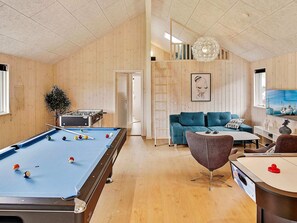 A room with a pool table, a sofa, a coffee table, and a ping pong table.
