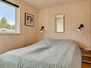 A bedroom with a bed, a window, a framed picture, and two wall-mounted lamps. - 5 Star Holiday Home in Vejby (Vejby)