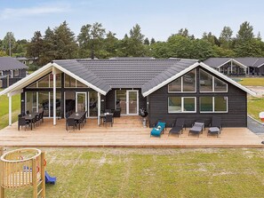 A modern house with a large deck, outdoor seating, and a garage. - 5 Star Holiday Home in Vejby (Vejby)