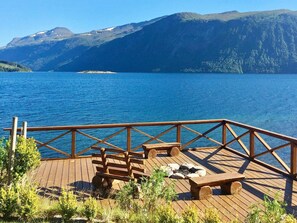 A wooden deck with benches overlooking a lake and mountains. - Holiday Home in EidsvÃ¥g (Molde)