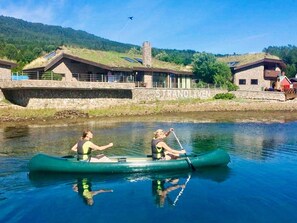 A green canoe on a calm river with a stone bridge and buildings in the background. - Holiday Home in EidsvÃ¥g (Molde)
