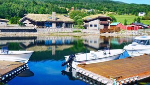 A lakeside property with a dock, boats, and buildings with a stone facade.