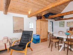 A cozy room with a wooden ceiling, a black leather chair, a wooden cabinet, a dining table with chairs, and a map on the wall. - 4 Star Holiday Home in Ribe (Ribe)