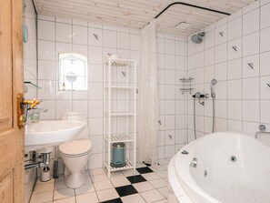 A bathroom with a white bathtub, a toilet, a sink, and a shower. - 4 Star Holiday Home in Ribe (Ribe)