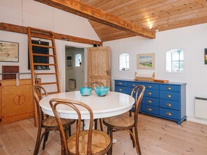 A dining area with a round table, four chairs, a wooden cabinet, and a blue dresser.