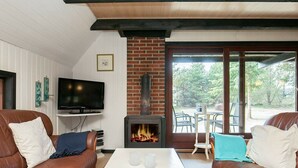 A cozy living room with leather sofas, a white coffee table, a TV, and a wood-burning stove. - Tranquil Holiday Home in Vestervig near Sea (Vestervig)