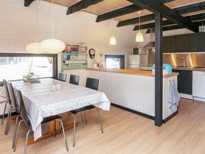 Une cuisine moderne dotée d’un îlot central, de planchers en bois et de luminaires suspendus.