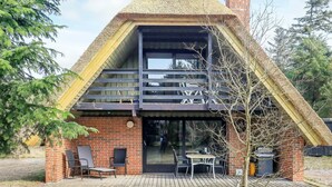 A modern house with a triangular roof, large windows, and a patio area with outdoor furniture. - Tranquil Holiday Home in Vestervig near Sea (Vestervig)