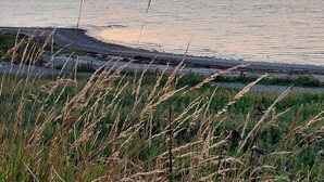 A sunset over a calm body of water with grassy foreground. - 5 Person Holiday Home in Vinderup (Vinderup)