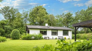 A white house with a tiled roof, surrounded by a well-maintained lawn and various plants. - 5 Person Holiday Home in Vinderup (Vinderup)