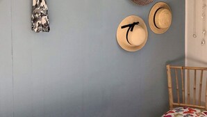 A bedroom with a bed, a chair with a floral cushion, and three hats on the wall. - 5 Person Holiday Home in Vinderup (Vinderup)