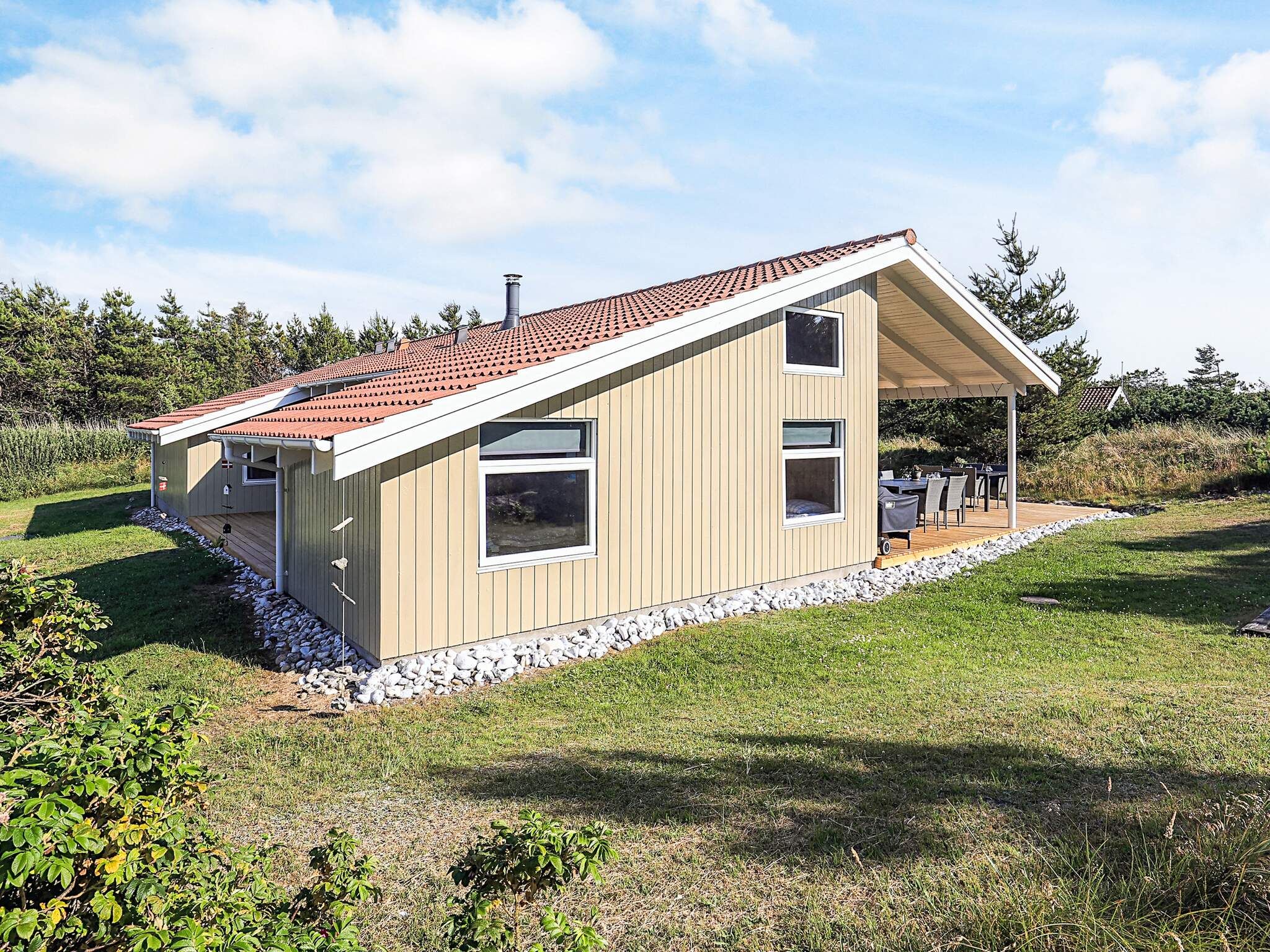 A modern single-story house with a sloped roof, large windows, and a covered patio area.