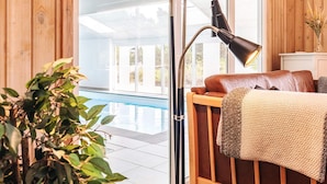 A bedroom with a wooden headboard, a large window, and a view of a swimming pool. - 5 Star Holiday Home in Thisted (Thisted)