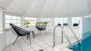 Un área de piscina con trampolín, dos sillas y una mesa.