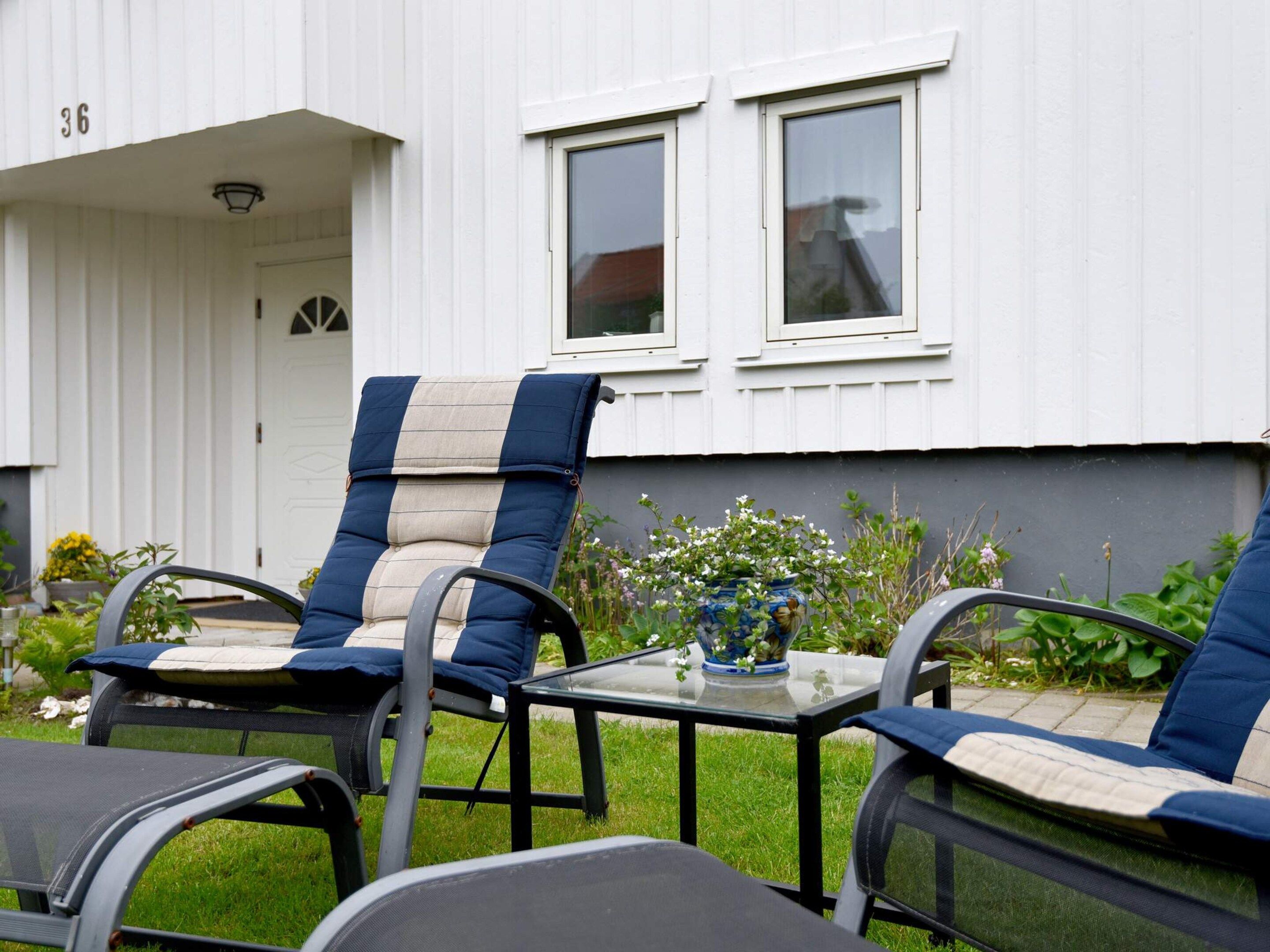 Un patio con mobiliario exterior, una mesa de vidrio y una planta en maceta.