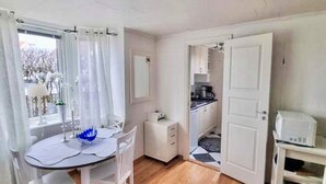 A room with a dining table, chairs, a small kitchenette, and a bed. - 3 Person Holiday Home in Lysekil (Lysekil)