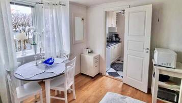 A room with a dining table, chairs, a small kitchenette, and a bed.