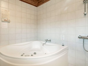 A bathroom with a white bathtub, a shower, and tiled walls.
