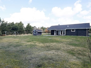 A residential property with a main house and a smaller shed, surrounded by a grassy yard and trees.