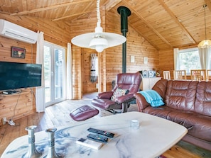 A wooden interior with a leather sofa, a television, and a marble table with remote controls.