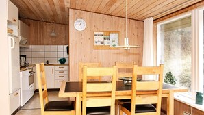 Puisesti sisustettu tila, jossa on ruokapöytä ja -tuolit, kello ja ikkuna, josta avautuu näkymä puihin.