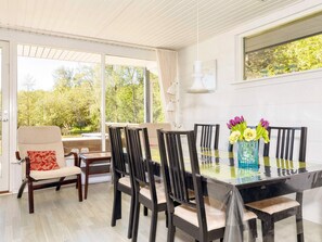 A dining area with a glass table, six chairs, and a vase with flowers. - 4 Star Holiday Home in Fur (Fur)