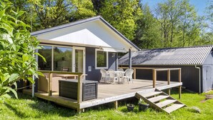 Una cabana moderna amb terrassa, seients exteriors i garatge.