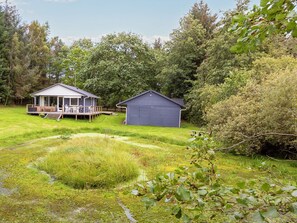 A house with a deck and a shed in a grassy area with trees. - 4 Star Holiday Home in Fur (Fur)