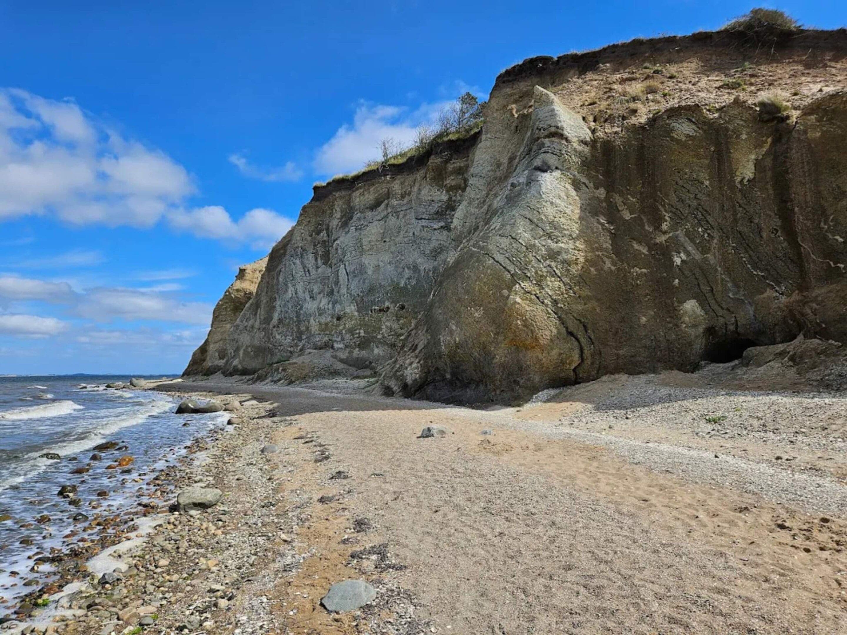 Un paisaje costero con un acantilado imponente y una playa arenosa.
