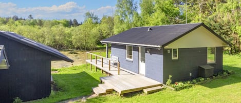Een laag gebouw met terras, omringd door groen en bomen.
