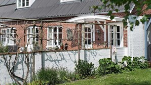 Una casa tradizionale in mattoni con tetto a falde, abbaini e un portico coperto.