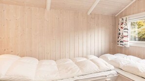 Ein Zimmer mit zwei Betten, Holzwänden und einem Fenster mit Vorhängen.