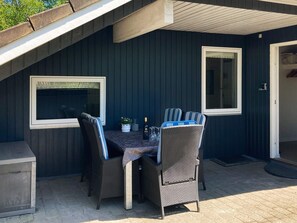 An outdoor patio with a table and chairs, a bottle of champagne, and a window. - 4 Star Holiday Home in Oksbol (Oksbol)