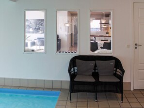 A room with a black wicker sofa, a tiled floor, and a view through a window. - 4 Star Holiday Home in Oksbol (Oksbol)