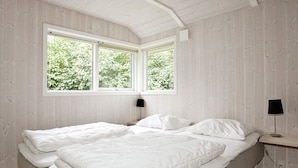A bedroom with two beds, a window with a view of greenery, and a bedside table with a lamp. - Cozy Holiday Home in Hadsund near Family Friendly Beach (Hadsund)