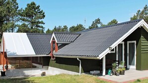 A row of cabins with sloped roofs, a covered porch, and a small garden area with potted plants. - 5 Person Holiday Home in Romo (Rømø)