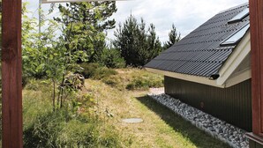 A covered outdoor area with a sloped roof, surrounded by trees and a gravel path. - 5 Person Holiday Home in Romo (Rømø)