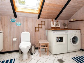 Efficient laundry room with a washing machine, dryer, and toilet, plus a small stool and storage.