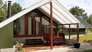 A modern house with a sloped roof, wooden exterior, and a covered patio area with a table and chairs. - 5 Person Holiday Home in Romo (Rømø)