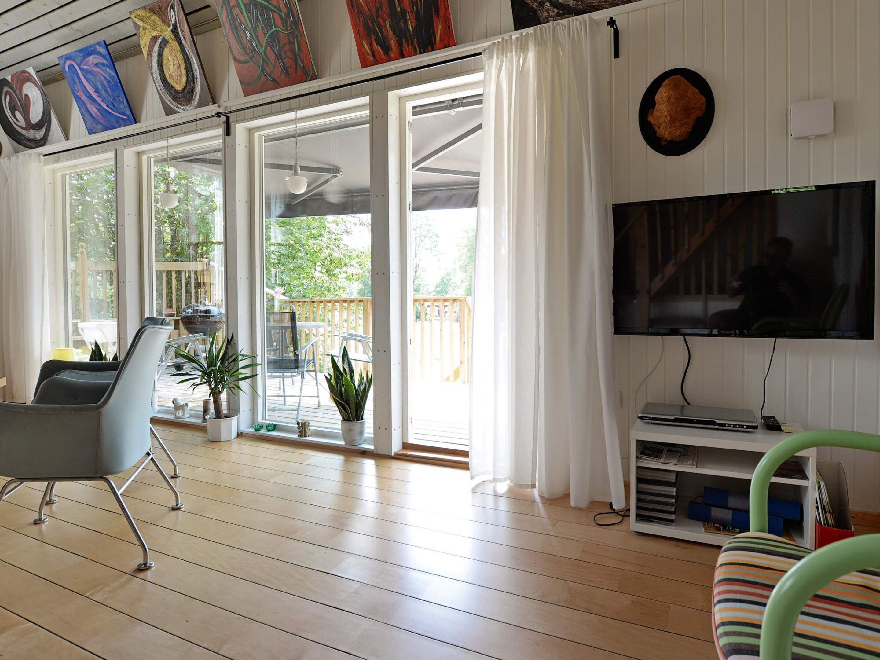 Amplia sala de estar con un televisor grande, un sillón cómodo y un ventanal corredizo que da a un patio exterior.