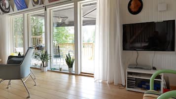 Amplia sala de estar con un televisor grande, un sillón cómodo y un ventanal corredizo que da a un patio exterior.