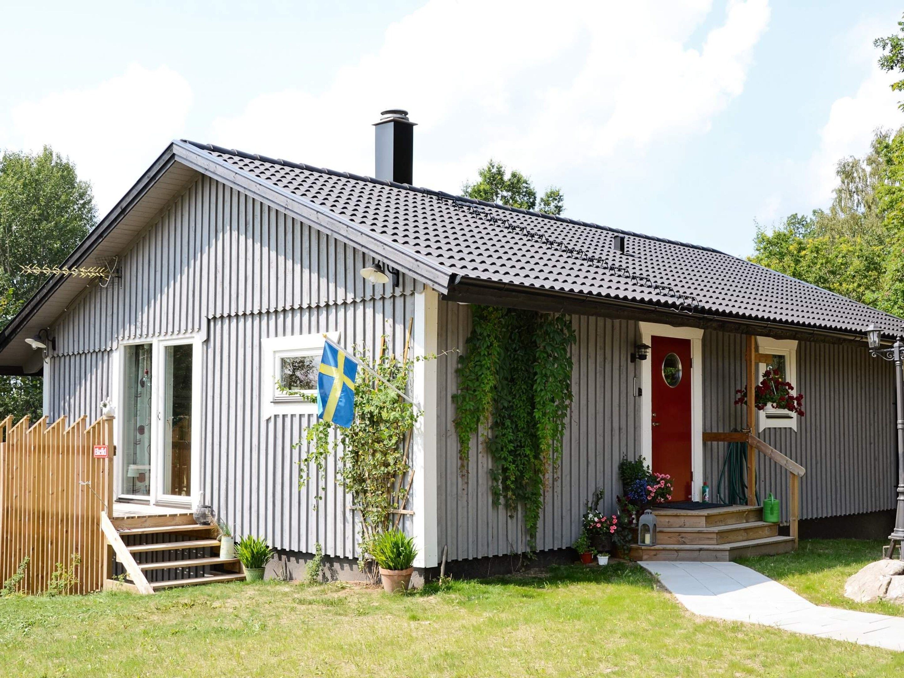 A single-story building with a sloped roof, a red door, and a flag.
