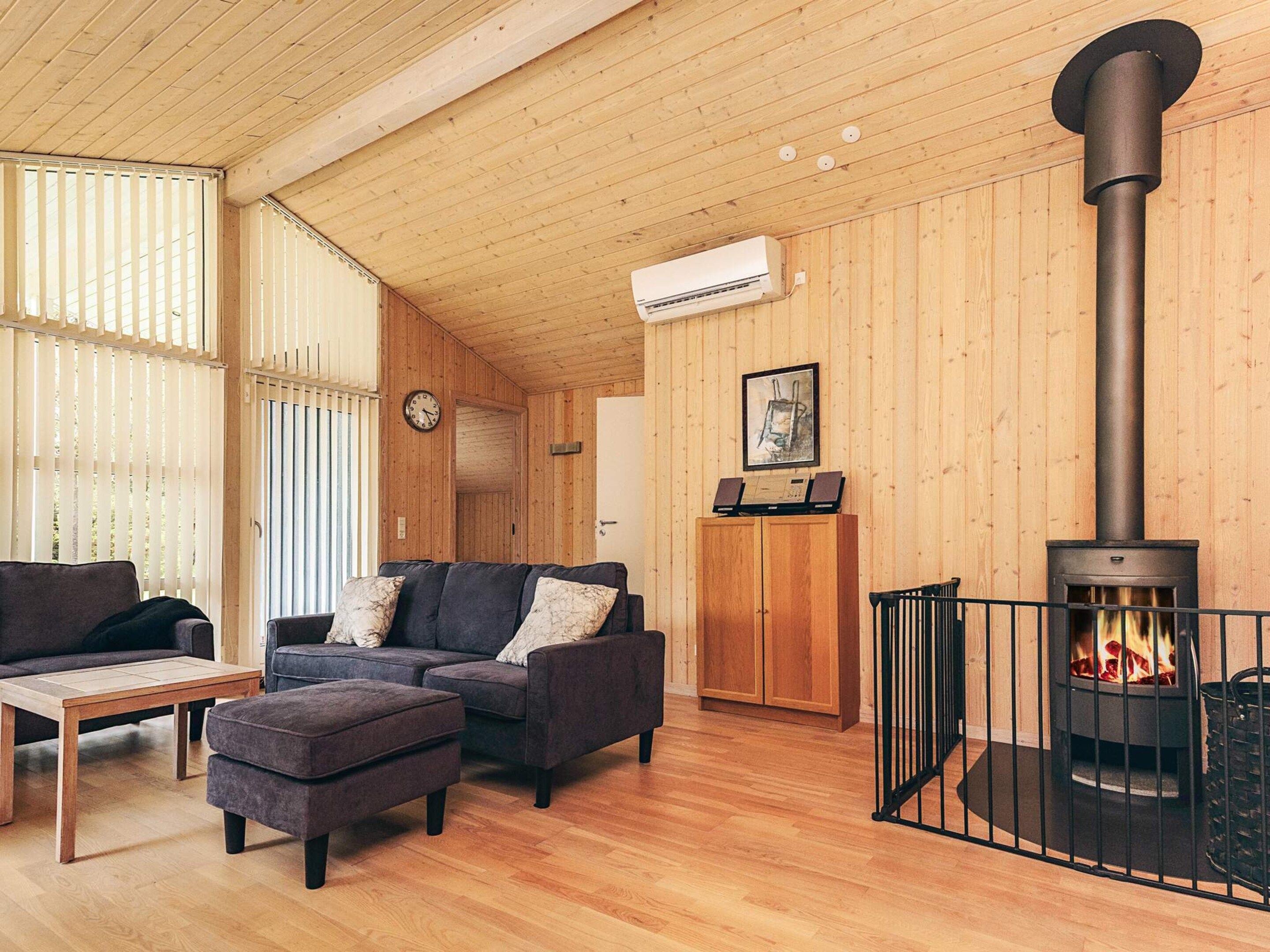 Una sala acogedora con chimenea, paredes de madera y un sofá.