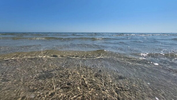 A beach with clear water and a clear sky.
