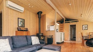 A cozy cabin interior with a sofa, a table, a fireplace, and wooden walls.