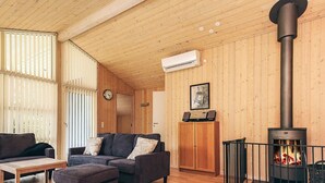A cozy living room with a wooden ceiling, a fireplace, a sofa, and a coffee table.