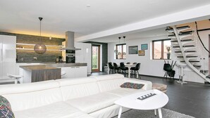Un espai de vida modern amb un sofà blanc, una zona de menjador i una cuina.